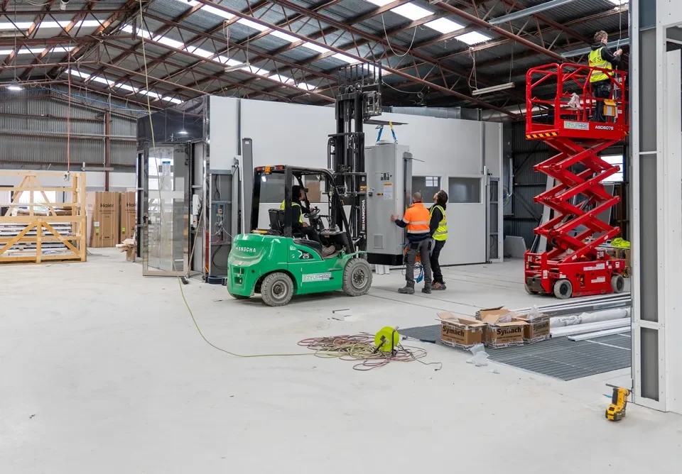 Workers using forklifts and scissor lifts inside a warehouse